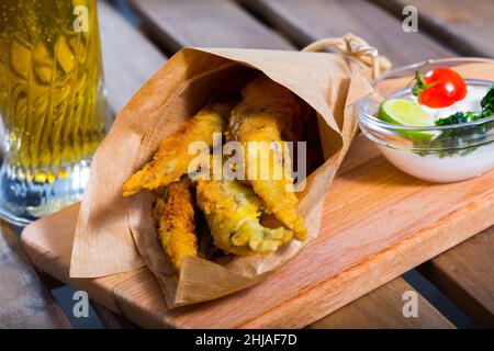 Acciughe fritte in padella con salsa cremosa al formaggio, verdure Foto Stock