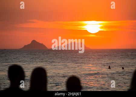 silhouette di persone che guardano il tramonto alla spiaggia di arpoador a rio de janeiro, brasile. Foto Stock