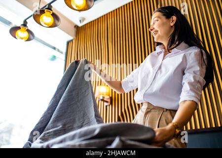 donna indiana che fissa il tavolo per la cena nella sala luce del giorno Foto Stock