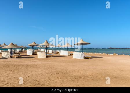 Hurghada, Egitto - 03 giugno 2021: Ombrelloni e lettini da mare su una spiaggia vuota del Labranda Club Hotel situato nella Baia di Makadi, che una delle bea egiziane Foto Stock