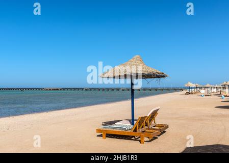 Hurghada, Egitto - 03 giugno 2021: Ombrelloni e lettini da mare su una spiaggia vuota della Royal Pharaohs Makadi Bay, che uno di Egitto bello Mar Rosso R Foto Stock