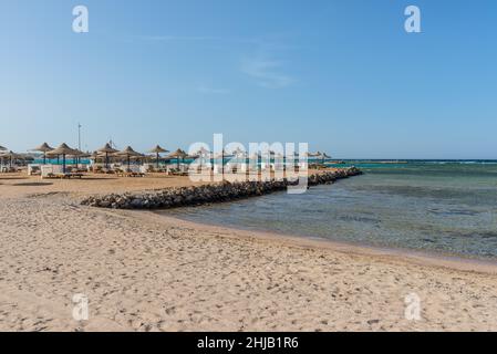 Hurghada, Egitto - 03 giugno 2021: Ombrelloni e lettini da mare su una spiaggia vuota della Royal Pharaohs Makadi Bay, che uno di Egitto bello Mar Rosso R Foto Stock