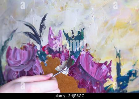 Donna pittura mani con palette coltelli fiori da olio vernici su legno compensato Foto Stock