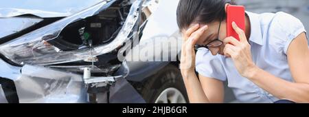 Donna sconvolto che parla al telefono sullo sfondo di un'auto rotta Foto Stock