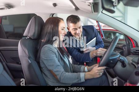 L'assistente del negozio maschile mostra le fature femminili del cliente della sua nuova auto che ha appena comprato. Foto Stock