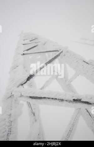 polo elettrico della stazione trasmittente coperto di neve Foto Stock