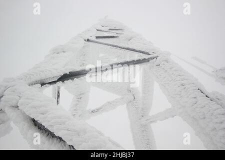 polo elettrico della stazione trasmittente coperto di neve Foto Stock