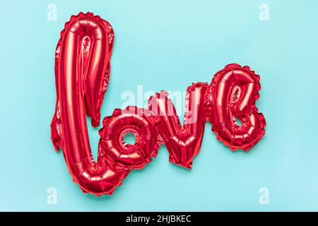 Lettere gonfiabili amore in rosso isolato su sfondo blu piatto Lay Top view Holiday card, Happy San Valentino concetto Amore in aria Foto Stock