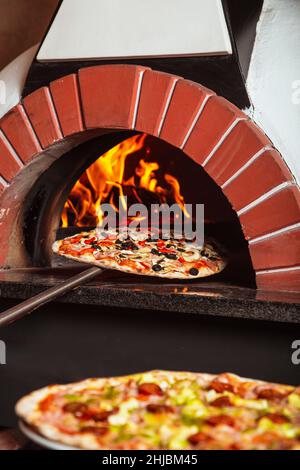 Italian pizza cotta nel forno a legna. Foto Stock