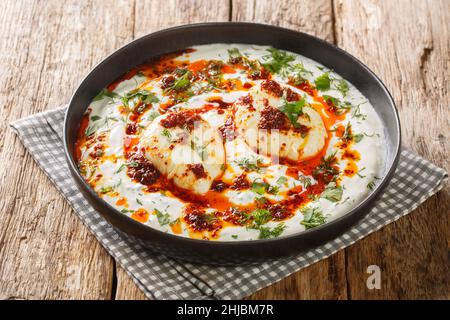 Uova turche con yogurt all'aglio e burro piccante condimento primo piano in un piatto sul tavolo. Orizzontale Foto Stock
