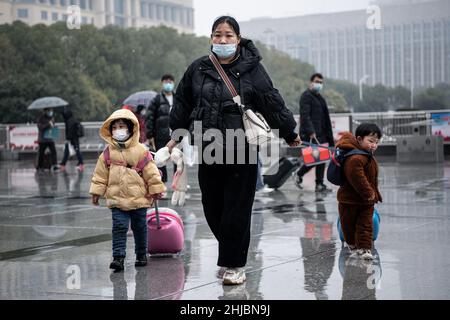 Wuhan, Cina. 28th Jan 2022. Una donna con i suoi figli cammina nella nevicata alla stazione ferroviaria di Hankou a Wuhan.Un totale di 2,8 miliardi di viaggi passeggeri sono attesi durante i 40 giorni 'Chunyun, ' o Spring Festival corsa, che ha iniziato dal 17 gennaio di quest'anno. Milioni di cinesi si recheranno a casa per visitare le famiglie in massa durante il periodo di festa di Primavera che inizia con il Capodanno lunare il 1 febbraio. (Foto di Ren Yong/SOPA Images/Sipa USA) Credit: Sipa USA/Alamy Live News Foto Stock