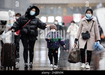 Wuhan, Cina. 28th Jan 2022. Una donna con il suo bambino a piedi nella nevicata alla stazione ferroviaria di Hankou a Wuhan.Un totale di 2,8 miliardi di viaggi passeggeri sono attesi durante i 40 giorni 'Chunyun, ' o corsa di viaggio Festival di primavera, che ha iniziato dal 17 gennaio di quest'anno. Milioni di cinesi si recheranno a casa per visitare le famiglie in massa durante il periodo di festa di Primavera che inizia con il Capodanno lunare il 1 febbraio. (Foto di Ren Yong/SOPA Images/Sipa USA) Credit: Sipa USA/Alamy Live News Foto Stock