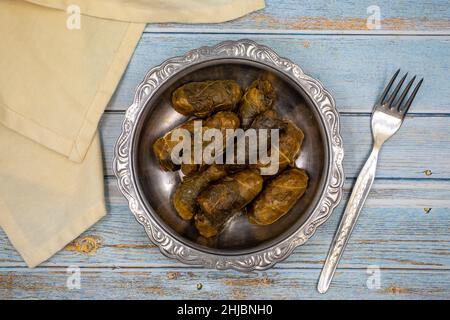 Confezionamento di foglie di carne. Sapore mediterraneo tradizionale. Foglie avvolte con yogurt su sfondo blu. Nome locale etli yaprak sarma Foto Stock