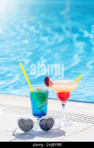 Due colorati bicchieri da cocktail ai bordi della piscina. Con spazio per la copia Foto Stock