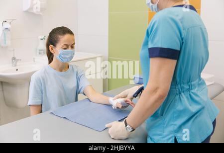 Un medico si è avvolto intorno al polso per primo soccorso. Applicazione di bende sulle mani del paziente, concetti di pronto soccorso e lesioni al polso Foto Stock