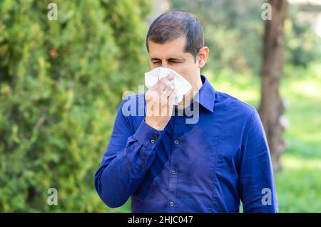 L'uomo malato che soffia utilizzando un tessuto in un parco Foto Stock