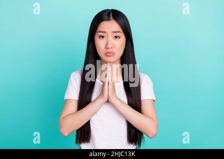 Ritratto di attraente miserabile speranza ragazza dai capelli lunghi che prega isolato su sfondo di colore turchese teale brillante Foto Stock