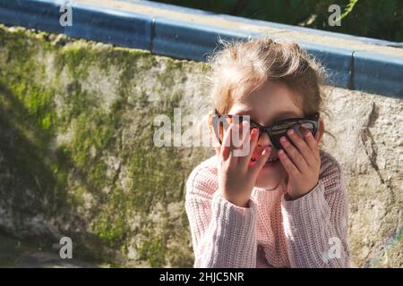 Carina bambina giocosamente indossando grandi occhiali da sole e divertendosi Foto Stock