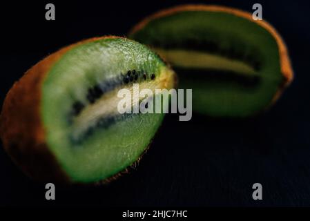 macro primo piano di un kiwi tagliato a metà su sfondo scuro Foto Stock