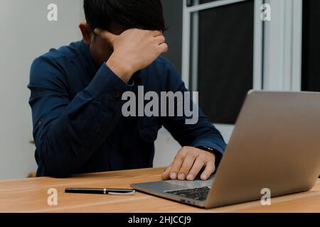 Uomo d'affari che si sente malato e stanco mentre si siede al suo posto di lavoro in ufficio di concetto di scadenza Foto Stock