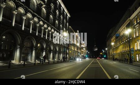 Strada cittadina con architettura antica sullo sfondo della torre di notte. Azione. Strada trafficata con architettura antica, luminosa di notte. La gente cammina Foto Stock