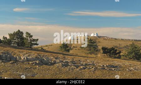 Vista dall'alto degli edifici a cupola bianca degli osservatori sulla collina. Scatto. Strutture di ricerca astronomica e grandi osservatori situati in cima con belle Foto Stock