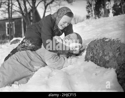 Inverno nel 1940s. Le due ragazze stanno giocando nella neve che ride. Uno sopra l'altro mettendo la neve in faccia. Sono lavoratori di una fattoria in Svezia durante la seconda guerra mondiale e hanno assunto il ruolo di lavoratori maschi quando invece erano nell'esercito svedese e spesso posti al confine svedese lontano. Rotebro Svezia Febbraio 1940. Kristoffersson Ref 78-3 Foto Stock