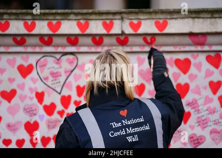 Un volontario del gruppo della campagna delle famiglie di giustizia covid-19 dipinge un cuore sul National Covid Memorial Wall di fronte al Palazzo di Westminster nel centro di Londra, che ricorda le persone che sono morte del virus. Data foto: Venerdì 28 gennaio 2022. Foto Stock
