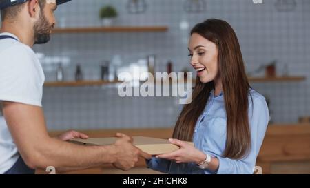 Donna sorridente che prende la scatola della pizza dal corriere a casa Foto Stock