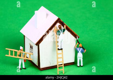 Immagine concettuale di decoratori di figure in miniatura che dipingono le pareti di una casa modello Foto Stock