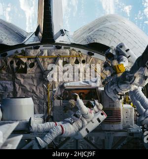 Fotografato il 11 ottobre 1984 attraverso le finestre del ponte di poppa dello Space Shuttle Challenger, questo telaio del 70mm mostra gli astronauti David C. Leestma, a sinistra, e Kathryn D. Sullivan presso il sistema di rifornimento orbitale (ORS) nel vano di poppa. La parte del Dr. Sullivan dell'attività extravehicular (EVA) rappresentò la prima impresa di questo tipo per una donna americana. Foto Stock