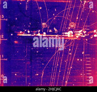 Evento camera di bolla: Particelle che passano attraverso la schermatura del piombo. Novembre 17, 1964. Camera di bolla-1408. La schermatura al piombo si riferisce all'uso del piombo come forma di protezione dalle radiazioni per proteggere persone o oggetti dalle radiazioni in modo da ridurre la dose effettiva. Il piombo può attenuare efficacemente alcuni tipi di radiazioni a causa della sua elevata densità e del suo elevato numero atomico; principalmente, è efficace nell'arrestare i raggi gamma e i raggi X. Una camera a bolla è un recipiente riempito con un liquido trasparente surriscaldato (il più delle volte idrogeno liquido) utilizzato per rilevare particelle caricate elettricamente che si muovono attraverso di esso. Foto Stock