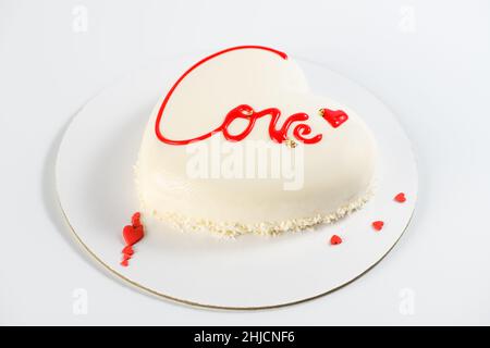 Una torta a forma di cuore. Mousse la torta leggera a forma di cuore con l'iscrizione amore su sfondo grigio. Dolce San Valentino. San Valentino Foto Stock