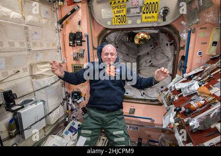 Merenda tempo sulla Stazione spaziale Internazionale come astronauta della NASA Scott Kelly guarda un mazzo di carote fresche galleggiare davanti a lui durante la spedizione 43 nel mese di aprile 2015. Scott è uno dei membri dell'equipaggio di un anno sulla stazione per testare come il corpo umano reagisce ad una presenza estesa nello spazio, in preparazione ai lunghi voli che la NASA prevede per Marte e ritorno nel futuro. Foto Stock