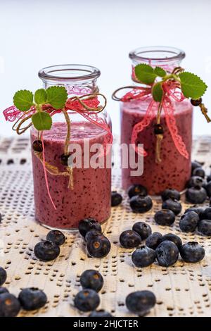 Due bottiglie decorate con nastri di delizioso yogurt sano, frullato, frullato mirtillo Foto Stock