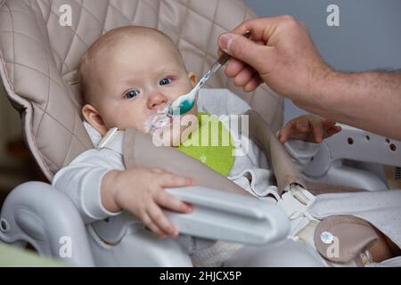 Il padre nutre il bambino caucasico con un cucchiaio. Una famiglia felice, un padre amorevole è un uomo che cuoca e alimenta alimenti sani ai bambini piccoli bambino, s Foto Stock