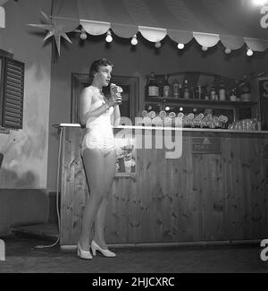 Donna nel 1950s. Una giovane donna è in piedi in un bar con un drink in mano sorseggiandolo con una paglia. Lei indossa abiti che dal theate o una varietà di spettacolo. Svezia 1956. rif Kristoffersson BE78-2 Foto Stock