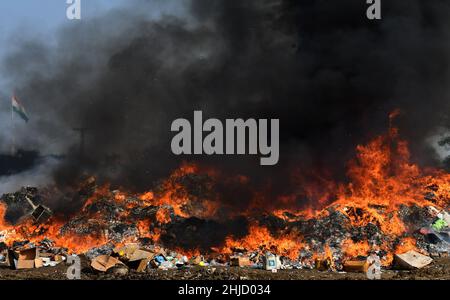 Lahore, Pakistan. 26th Jan 2022. I funzionari doganali pakistani bruciano per distruggere le merci contrabbandate (sigarette, tabacco da masticare, noci di Betel, fuochi d'artificio e altre cose vicino al confine di Wagha alla vigilia della giornata doganale mondiale a Lahore, Pakistan, il 26 gennaio 2022. Un pile di farmaci confiscati, sigarette e altri beni sequestrati da diverse aree, durante la cerimonia di lancio di campagne di sensibilizzazione in tutta la provincia, organizzato dalla dogana pakistana tenutasi al confine di Wagha a Lahore (Foto di Rana Sajid Hussain/Pacific Press/Sipa USA) Credit: Sipa USA/Alamy Live News Foto Stock