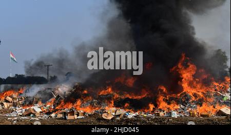 Lahore, Pakistan. 26th Jan 2022. I funzionari doganali pakistani bruciano per distruggere le merci contrabbandate (sigarette, tabacco da masticare, noci di Betel, fuochi d'artificio e altre cose vicino al confine di Wagha alla vigilia della giornata doganale mondiale a Lahore, Pakistan, il 26 gennaio 2022. Un pile di farmaci confiscati, sigarette e altri beni sequestrati da diverse aree, durante la cerimonia di lancio di campagne di sensibilizzazione in tutta la provincia, organizzato dalla dogana pakistana tenutasi al confine di Wagha a Lahore (Foto di Rana Sajid Hussain/Pacific Press/Sipa USA) Credit: Sipa USA/Alamy Live News Foto Stock