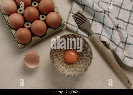 Uova, spazzola per pasticceria e asciugamano da cucina su un tavolo di marmo. Applicazione dell'uovo liquido Foto Stock