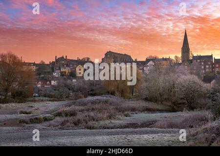 Dopo un pesante gelo notturno, all'alba il cielo diventa rosa su Malmesbury e l'antico ponte di crapper che conduce verso la storica collina segno Foto Stock