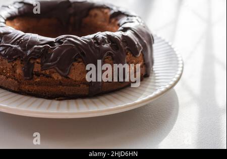 Una torta intera al cioccolato con glassa di fondente. Retroilluminazione dalla luce naturale della finestra della fotocamera. Foto Stock