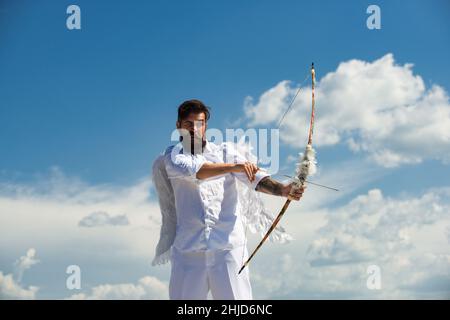 San Valentino concetto. Divertente angelo Cupido puntando con arco e freccia su uno sfondo cielo in cielo. Foto Stock