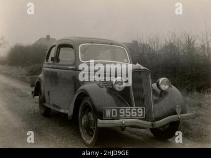 1940s, storico, al mattino presto e un fangoso Ford Model C Ten, parcheggiato su una corsia da un hedgerow, Essex, Inghilterra, Regno Unito. La vettura è stata fabbricata in Gran Bretagna tra il 1934 e il 1937, con i 'dieci' relativi alla sua potenza fiscale britannica del 10. Foto Stock