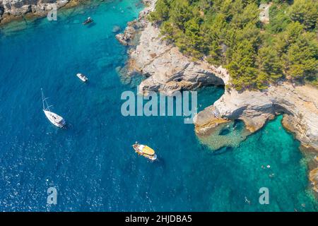 Vista aerea di yacht di lusso e barche a vela vicino alla costa rocciosa nella laguna Foto Stock