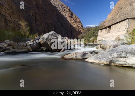 Creek tra montagne con una casa e alberi accanto Foto Stock