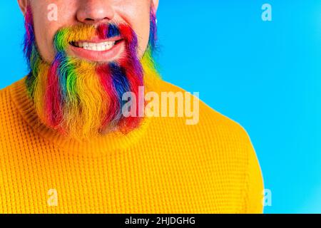 bell'uomo con raindow in barba e maglione giallo in baclground blu studio Foto Stock