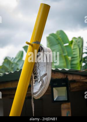 Una scarpa appeso su un tubo di metallo giallo per asciugare al sole Foto Stock