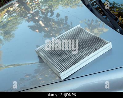 Il filtro aria sporco rimosso si trova sul cofano della vettura. Sostituzione del filtro dell'aria usato per auto Foto Stock