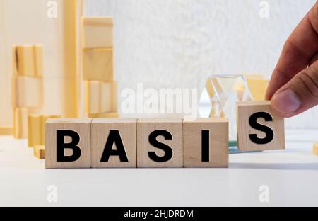 La parola BASE è scritta su cubi di legno che si trovano sul tavolo da ufficio di fronte a un computer portatile. Concetto aziendale. Foto Stock